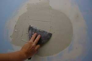 photo applying a coat of joint compound over plaster damage