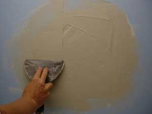photo applying a second coat of joint compound over damaged plaster