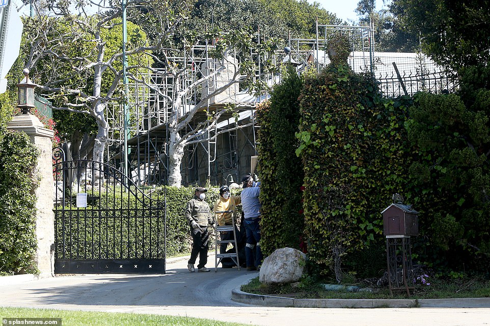 Three workers wearing protective face masks are seen outside the Playboy mansion. The landmark super-home in located in Holmby Hills